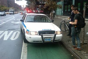 A cop tickets cyclists for not using the bike lane he is parking in.